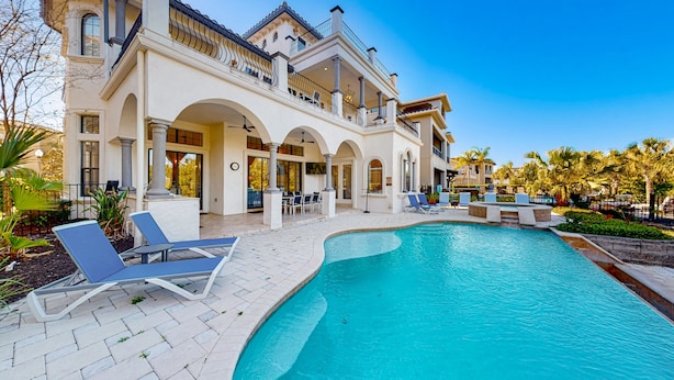 A large, two-story house with a swimming pool, outdoor seating, and a covered patio area. - Luxury Villa with Elegant Living Space at Reunion (Kissimmee)