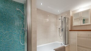 A modern bathroom with a glass-enclosed shower, a standalone bathtub, and a built-in toilet. - Contemporary three-bedroom apartment with free parking space. Sleeps 5. (Edinburgh)