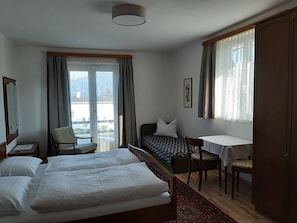 A hotel room with two beds, a desk, a chair, and a view of the outdoors.