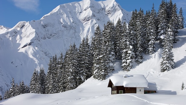 Une montagne enneigée avec un chalet.
