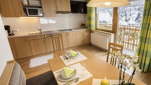 Une cuisine chaleureuse avec des meubles en bois, un four à micro-ondes et un coin repas avec une table mise pour deux personnes.