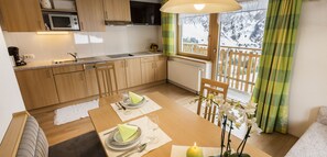 Eine gemütliche Küche mit Holzausstattung, einer Mikrowelle und einer Essecke mit Tisch für zwei Personen.