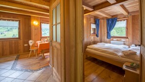 A wooden cabin with a dining area, a bedroom with a bed and a window, and a view of the outdoors. - MAS DE LA BOLP,  MOUNTAIN CHALET (Rabbi)