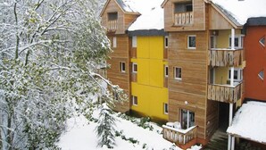 Un immeuble en bois à plusieurs étages, doté de balcons, entouré d’arbres couverts de neige.