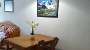 Un coin repas avec une table et des chaises en bois, un vase rempli de fleurs et un tableau encadré accroché au mur.