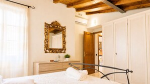 Un dormitorio con cama, cabecera de madera, espejo, cómoda y armario.