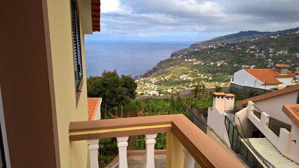 Un balcon donnant sur une ville côtière et la mer.