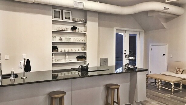 A modern kitchen with a central island, built-in shelves, and a view into the adjacent living room. - Historic downtown home a block from king st and 10-15 mins to the beach!  (Charleston)