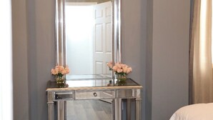 A mirrored vanity with two vases of flowers, a drawer, and a door in the background. - Historic downtown home a block from king st and 10-15 mins to the beach!  (Charleston)