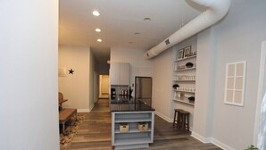 A modern kitchen with white cabinets, a black countertop, and a built-in oven. There is a small seating area with a bench and a rug. - Historic downtown home a block from king st and 10-15 mins to the beach!  (Charleston)