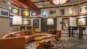 A lounge area with a curved leather sofa, a wooden coffee table, and a checkered rug. - Charlie's Slopeside: Best Location BC Village! Creekside Unit, Walk to Lifts, Ski School, Dining (Beaver Creek)