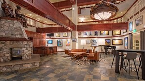 A spacious lobby with a stone fireplace, wooden ceiling beams, a large chandelier, and a seating area with a coffee table. - Charlie's Slopeside: Best Location BC Village! Creekside Unit, Walk to Lifts, Ski School, Dining (Beaver Creek)