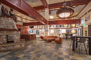A spacious lobby with a stone fireplace, wooden ceiling beams, a large chandelier, and a seating area with a coffee table. - Charlie's Slopeside: Best Location BC Village! Creekside Unit, Walk to Lifts, Ski School, Dining (Beaver Creek)