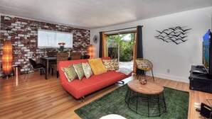 A living room with a red sofa, a round wooden table, and a brick wall.