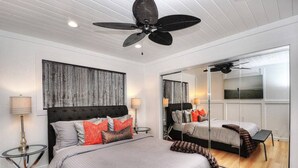 A modern bedroom with a large bed, a ceiling fan, and a large mirror reflecting the room.