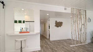 Una cocina moderna con armarios blancos, piso de madera y un adorno decorativo en la pared.