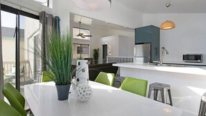 A modern kitchen with a white countertop, green chairs, and a potted plant. - Amber Back · Stunning Beach Townhouse, newly remodeled (Dana Point)