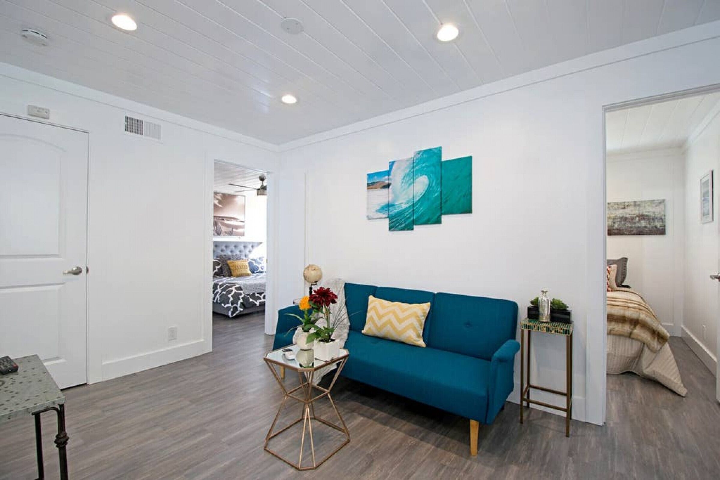 A modern living room with a teal sofa, a coffee table with decorative items, and a wall with abstract art.