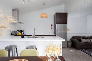 A modern kitchen with a white island, stainless steel appliances, and a hanging pendant light. - Fabulous Townhouse, close to beach, town and harbor (Dana Point)