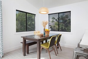 A dining area with a wooden table, two chairs, a hanging light fixture, and a window with blinds. - Fabulous Townhouse, close to beach, town and harbor (Dana Point)