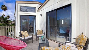 A modern outdoor patio with wicker furniture and large windows. - Fabulous Townhouse, close to beach, town and harbor (Dana Point)