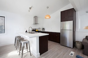A modern kitchen with a central island, stainless steel appliances, and bar stools. - Fabulous Townhouse, close to beach, town and harbor (Dana Point)