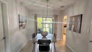 A dining area with a table, chairs, and a hanging light fixture.