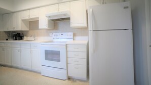 A kitchen with white cabinets, a white refrigerator, and a white stove.