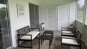 A sunroom with a seating area featuring a bench and tables, a ceiling fan, and a view through a window.
