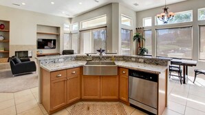 A modern kitchen with granite countertops, wooden cabinets, and a dishwasher. - Waterslide, heated pool home, PGA West 6th tee box (La Quinta)