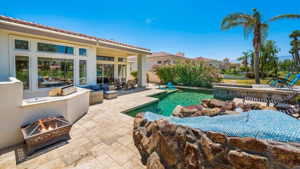 A poolside area with a fire pit, outdoor seating, and a view of the pool. - Waterslide, heated pool home, PGA West 6th tee box (La Quinta)