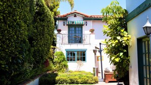A two-story building with a balcony, a small garden, and a wooden cart. - Garden Cottage Casita (San Clemente)