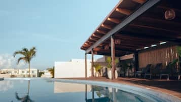 Alberca al aire libre, sombrillas en la alberca y camastros