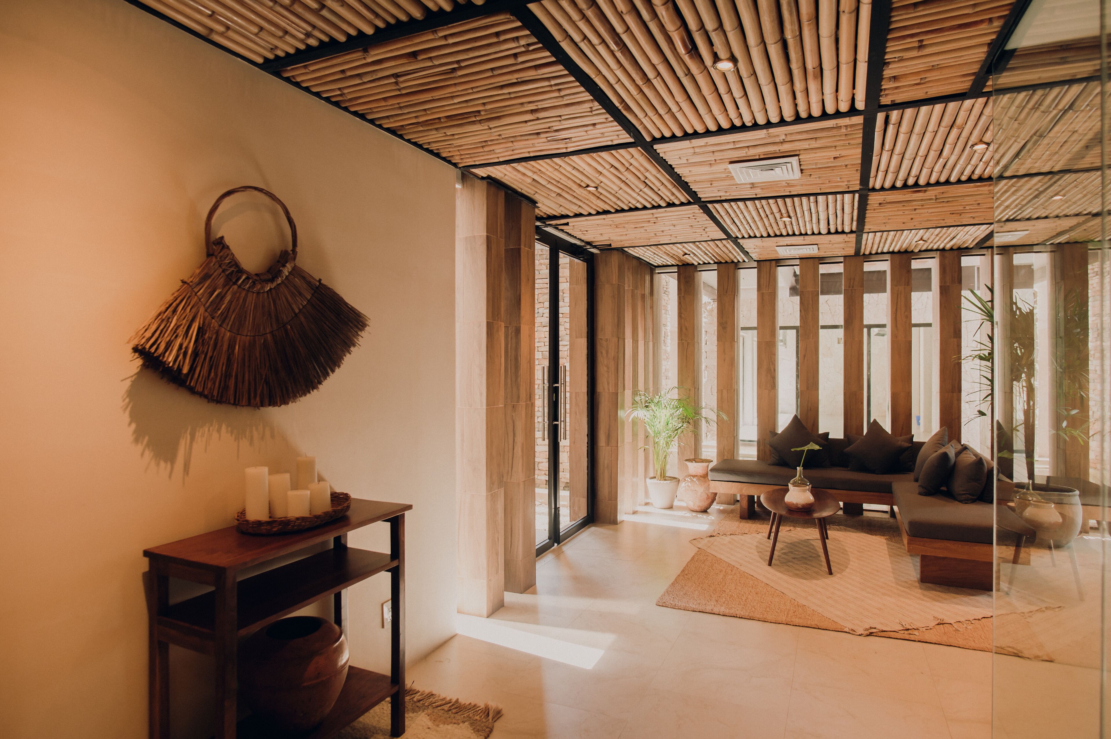 A modern living room with a bamboo ceiling, a sofa with cushions, a coffee table, and a wall-mounted decorative item.