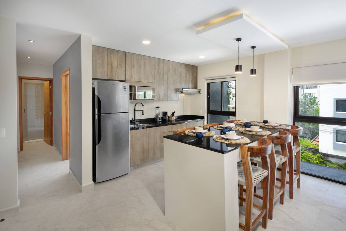 A modern kitchen with a central island, stainless steel appliances, and wooden cabinetry.