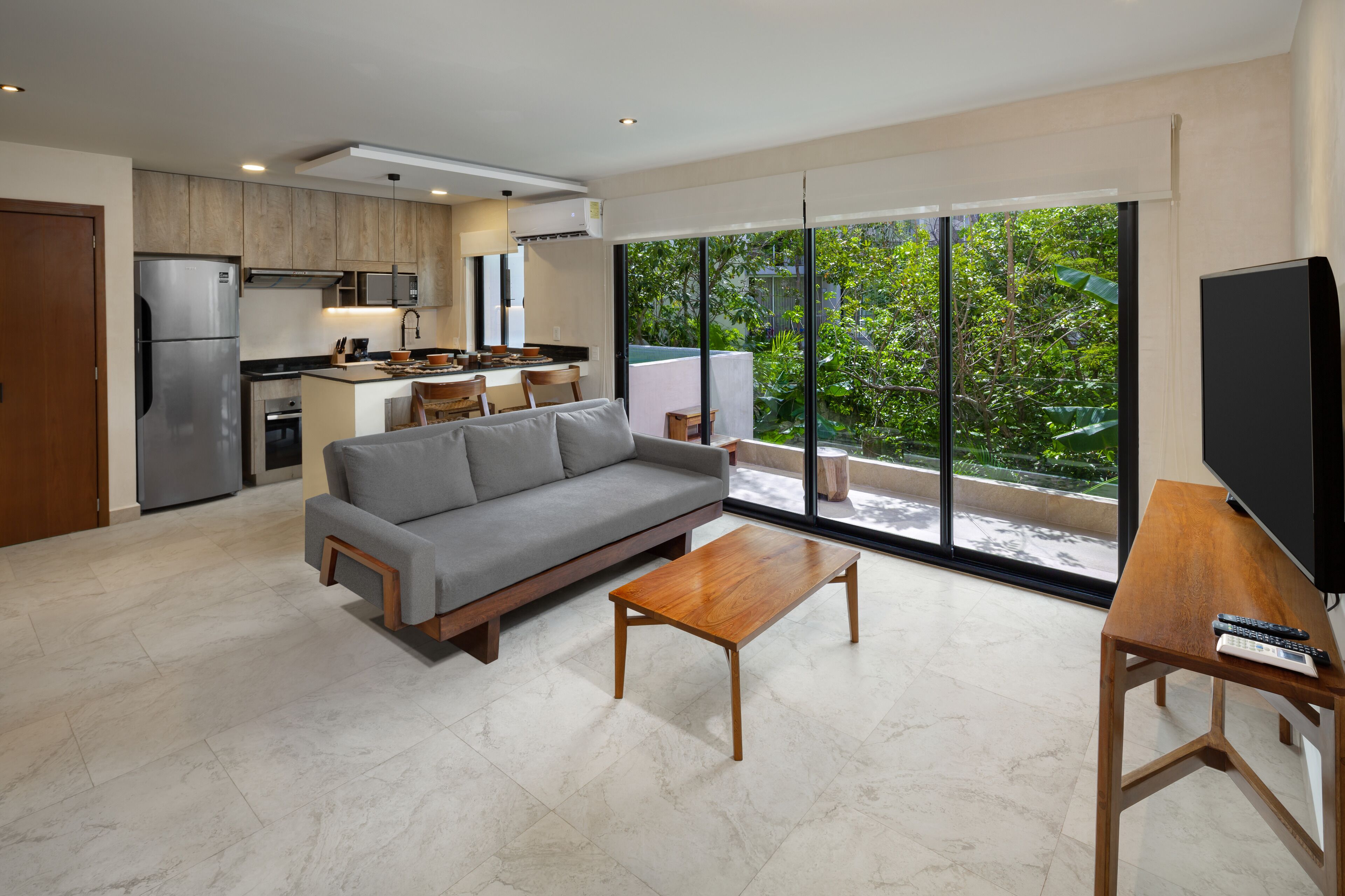 A modern living space with a grey sofa, wooden coffee table, and a TV on a wooden stand.