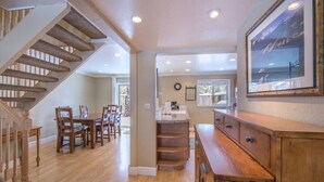 Una cocina amplia con armarios de madera, un comedor con mesa y sillas de madera, y una escalera que sube a otro nivel.