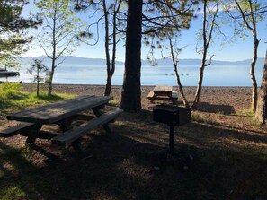A picnic table and a bench by a lake with trees and mountains in the background. - Walk to the lake (Tahoe City)