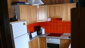 Una cocina con armarios de madera, un refrigerador blanco, una estufa y un salpicadero de azulejos rojos.