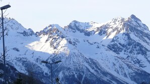 Un paisaje montañoso con picos nevados, un farol y un edificio en primer plano.