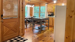 A wooden interior with a dining area, kitchen, and a door with a window. - Welcome to Bearadise! Charming cabin 10 minutes to downtown Blue Ridge! (Cherry Log)