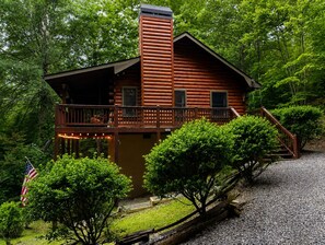 A log cabin with a balcony, a chimney, and a flag.