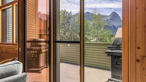 Una habitación con puerta de vidrio corredera que da a un balcón con vistas a las montañas.