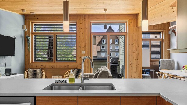 Una cocina moderna con paredes de madera, un ventanal grande y un lavamanos integrado.