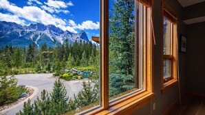 Ein Zimmer mit großen Fenstern und Blick auf eine gebirgige Landschaft, einschließlich Parkplatz und Grünflächen.