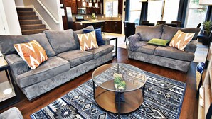 Ein modernes Wohnzimmer mit zwei grauen Sofas, einem Couchtisch und gemusterten Teppichen.