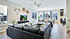 Ein modernes Wohnzimmer mit einer schwarzen Ledersofa, einem Flachbildfernseher und Wanddekorationen.