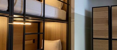 A bunk bed room with wooden paneling and a white mattress.