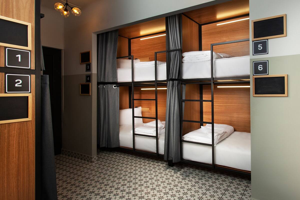 Een hotelkamer met stapelbedden, genummerde deuren en een patroon in de vloer.