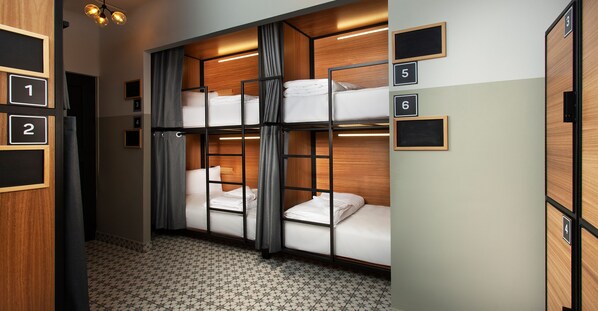A hotel room with bunk beds, numbered doors, and a patterned floor. - Hostal Casa MX Centro (Mexico City)